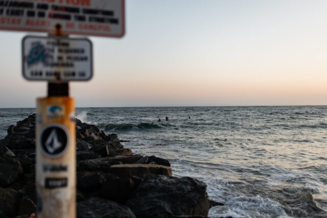 Pacific ocean from the shore with an out of focus sign and rocks in the foreground